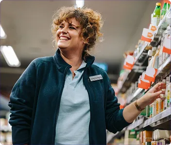 a retail employee smiling while walking down a store aisle